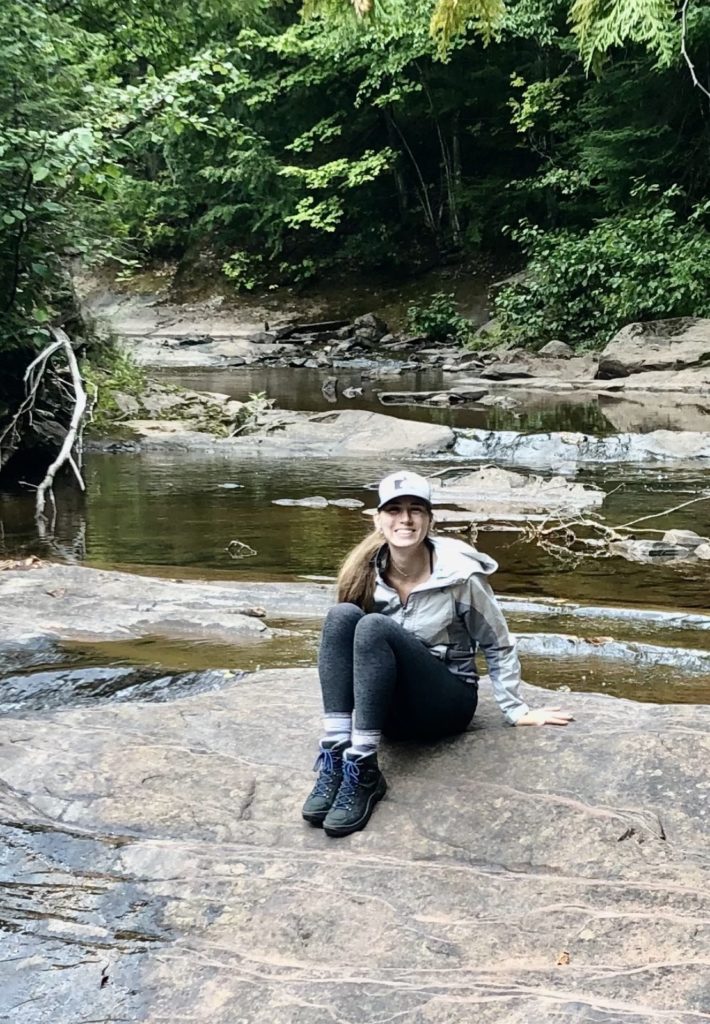 Ellen sitting on a rock in a stream in the woods